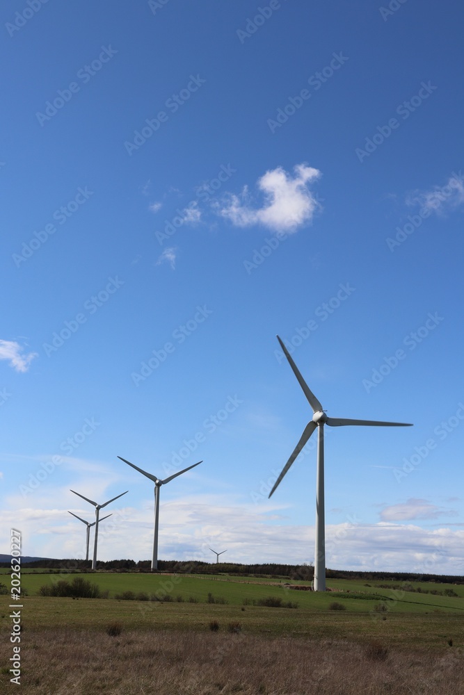 Wind turbines against blue sky with fluffy white clouds Wind turbines against blue sky with fluffy white clouds
