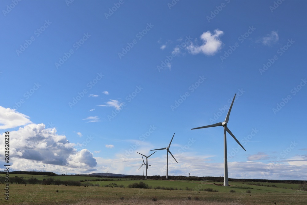 Wind tturbines against blue sky with fluffy white clouds Wind tturbines against blue sky with fluffy white clouds