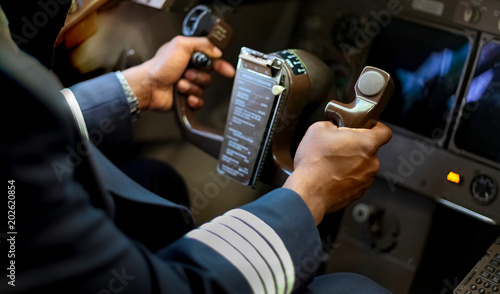 Foto Cropped Hands of African Pilot flying a commercial airplane, cockpit view close