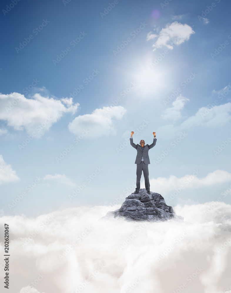 Happy businessman cheering against mountain peak through the clouds Happy businessman cheering against mountain peak through the clouds