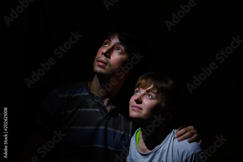 guy with a girl looking up against a dark background. low key