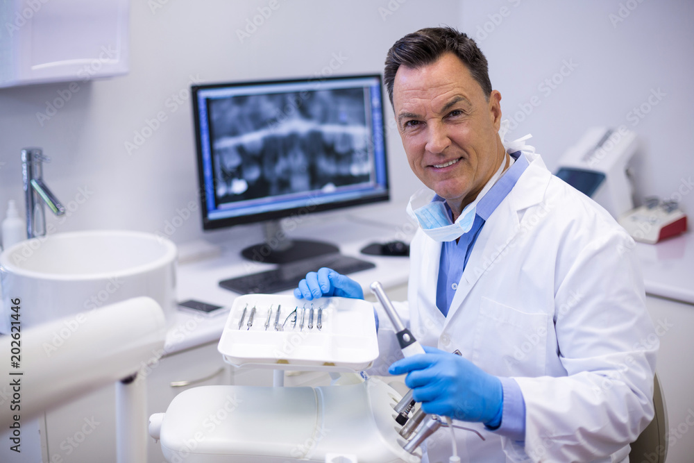 Portrait of smiling dentist holding dental hand piece Portrait of smiling dentist holding dental hand piece