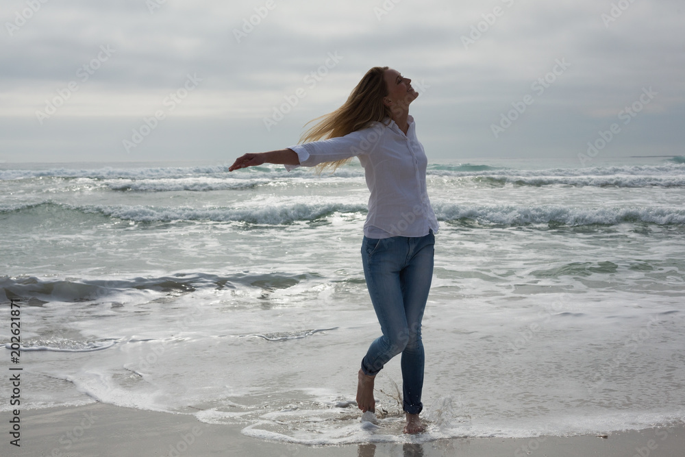 Woman with eyes closed and arms outstretched at beach