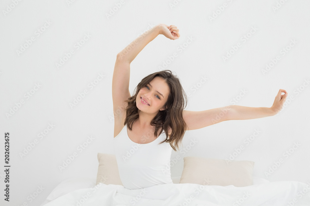 Smiling woman stretching her arms in bed Smiling woman stretching her arms in bed