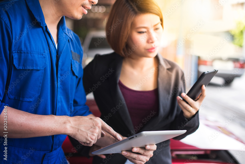 Asian beautiful customer is not satisfied while the mechanic explains the problem with her car, and talking on phone Asian beautiful customer is not satisfied while the mechanic explains the problem with her car, and talking on phone