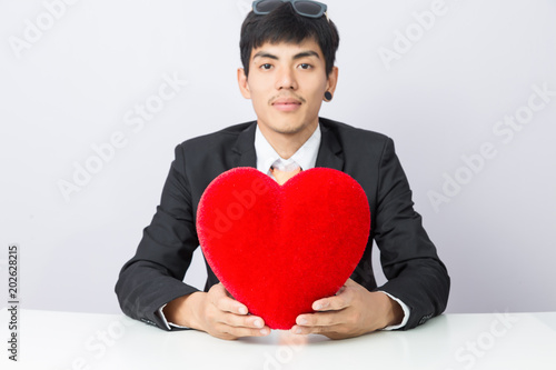 Businessman holds out the red heart, isolated background