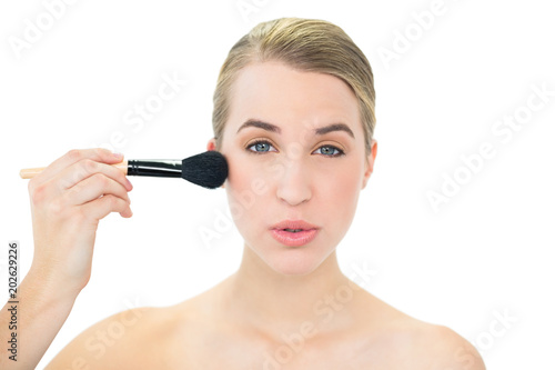 Content attractive blonde using blusher brush