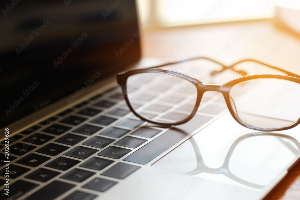 Eyes glasses put on computer laptop at business workplace in office with light background