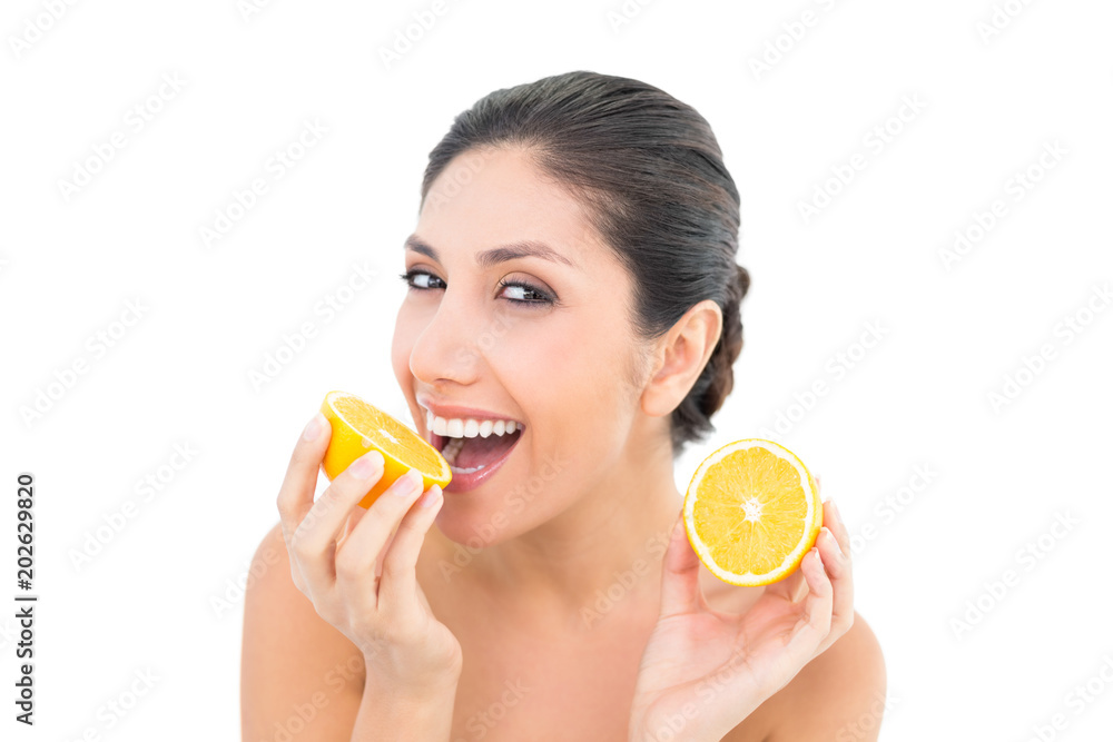 Pretty brunette holding two orange halves and smiling at camera Pretty brunette holding two orange halves and smiling at camera