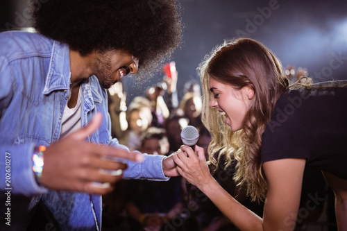 Cheerful woman singing with male singer at nightclub