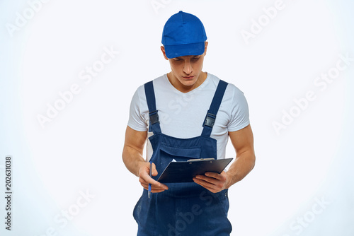 a man in a blue jumpsuit looks at the documents in his hand