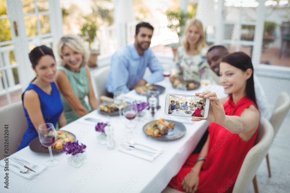 Friends taking selfie on mobile phone while having meal Friends taking selfie on mobile phone while having meal