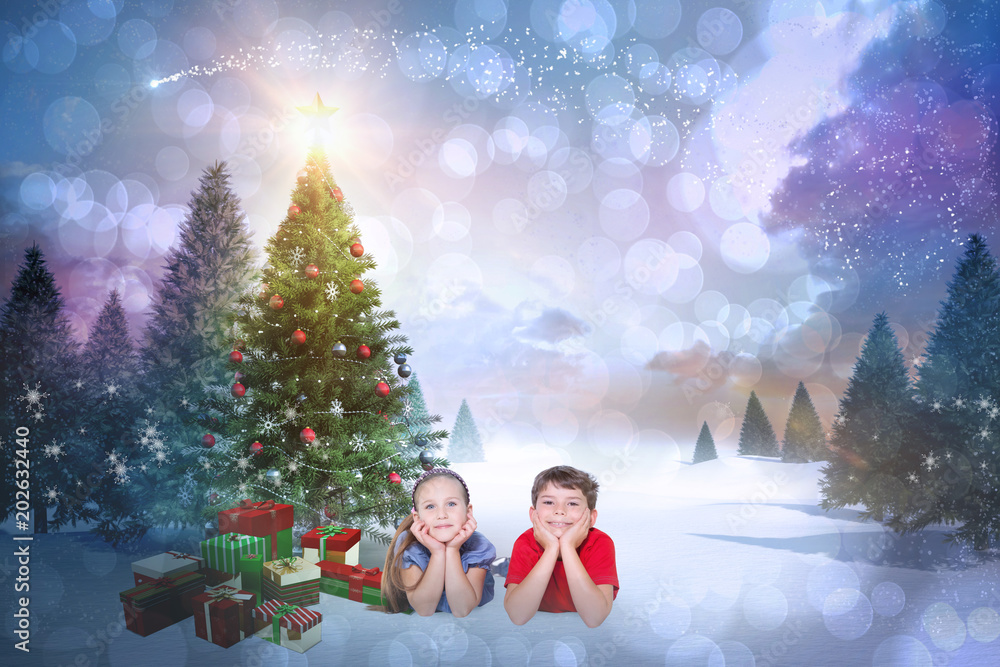 Composite image of cute children smiling at camera against snowy landscape with fir trees Composite image of cute children smiling at camera against snowy landscape with fir trees