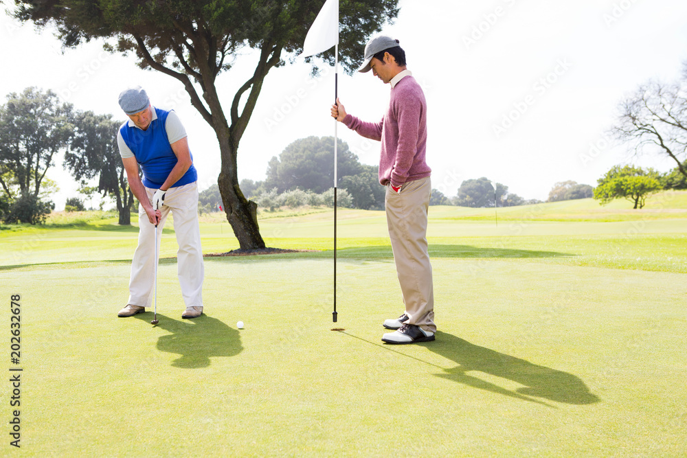 Obraz premium Golfer swinging his club with friend 