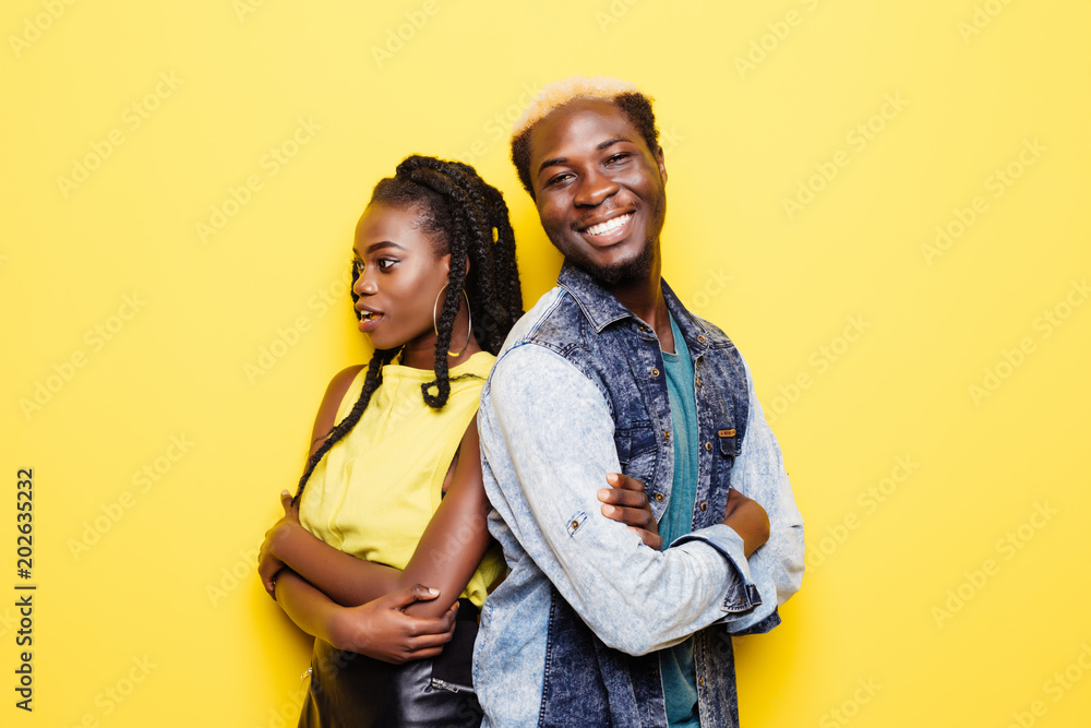 Fototapeta premium Portrait of afro american couple standing back to back isolated over yellow background