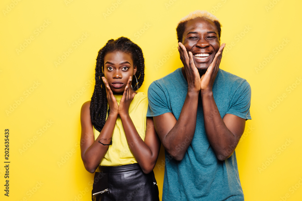 Portrait of a joyful young afro american couple screaming isolated over yellow background Portrait of a joyful young afro american couple screaming isolated over yellow background