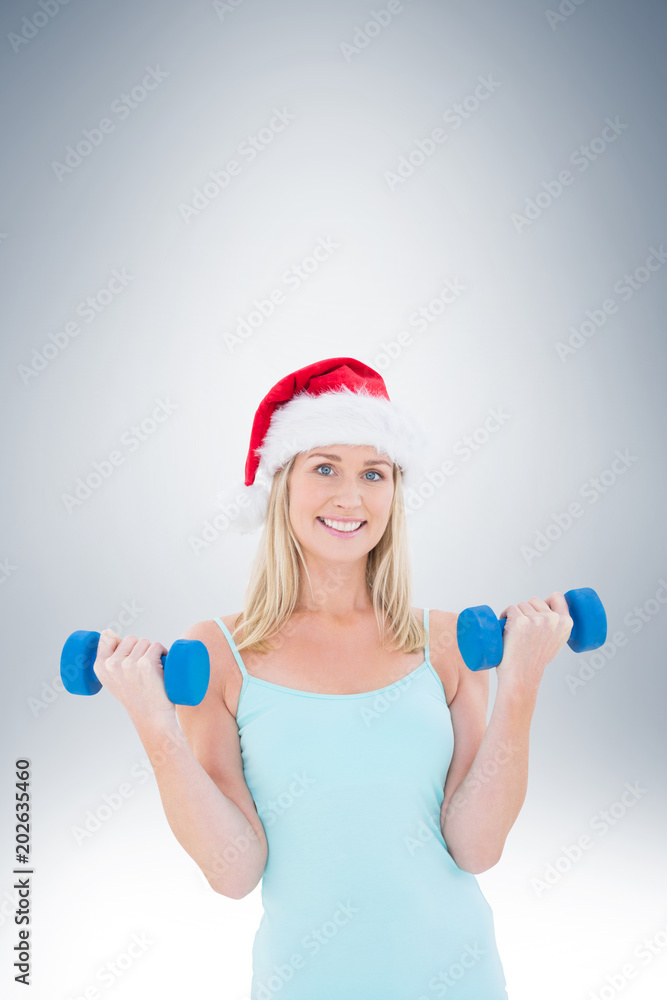Obraz premium Festive fit blonde holding dumbbells on vignette background