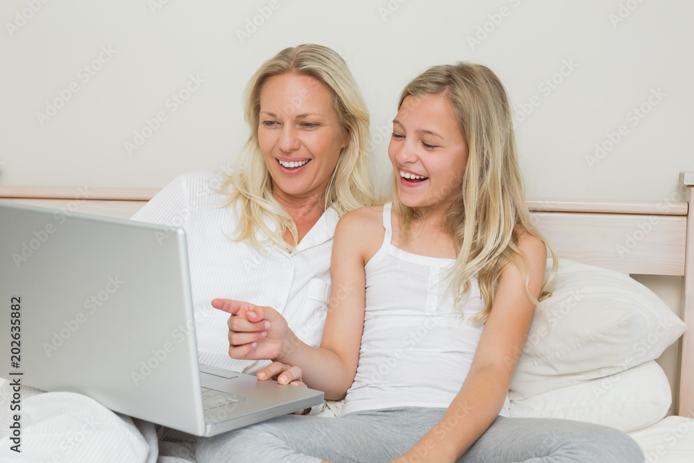 Mother and daughter using laptop together in bed Mother and daughter using laptop together in bed