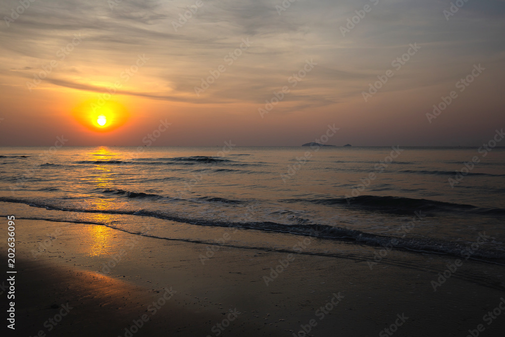 Nice sky, clouds and sun above the beautiful sea and sand beach with little waves at the morning moment.