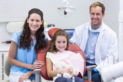 Portrait of dentist with young patient and her mother