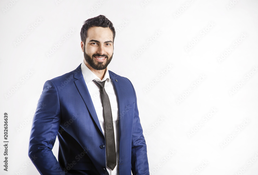 Portrait of bearded eastern smiling businessman dressed in blue suit and black tie on isolated white background Portrait of bearded eastern smiling businessman dressed in blue suit and black tie on isolated white background