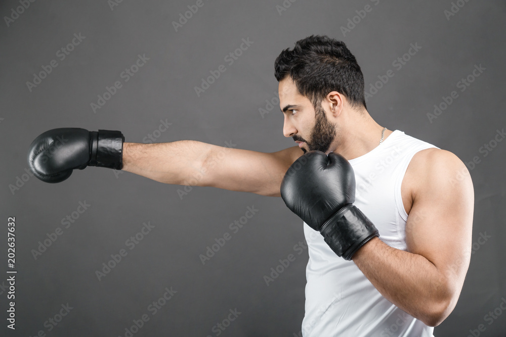 Handsome bearded man in boxing gloves and white shirt on isolated grey background