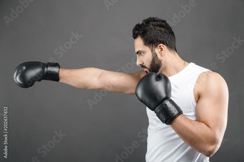 Handsome bearded man in boxing gloves and white shirt on isolated grey background © proimagecontent