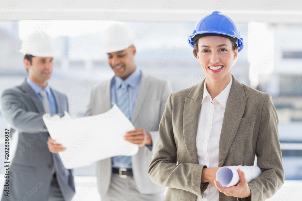 Businessmen and a woman with hard hats and holding blueprint Businessmen and a woman with hard hats and holding blueprint