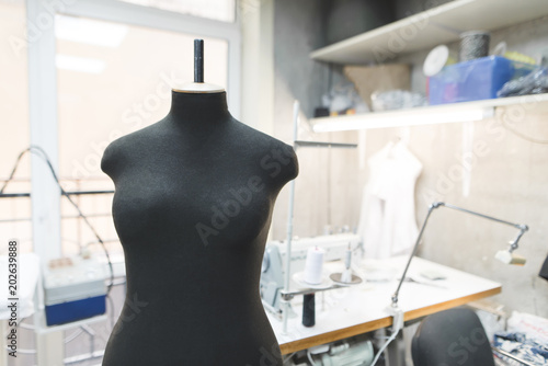 Black sewing mannequin on a background of workplace seamstresses. Sewing concept. © bodnarphoto