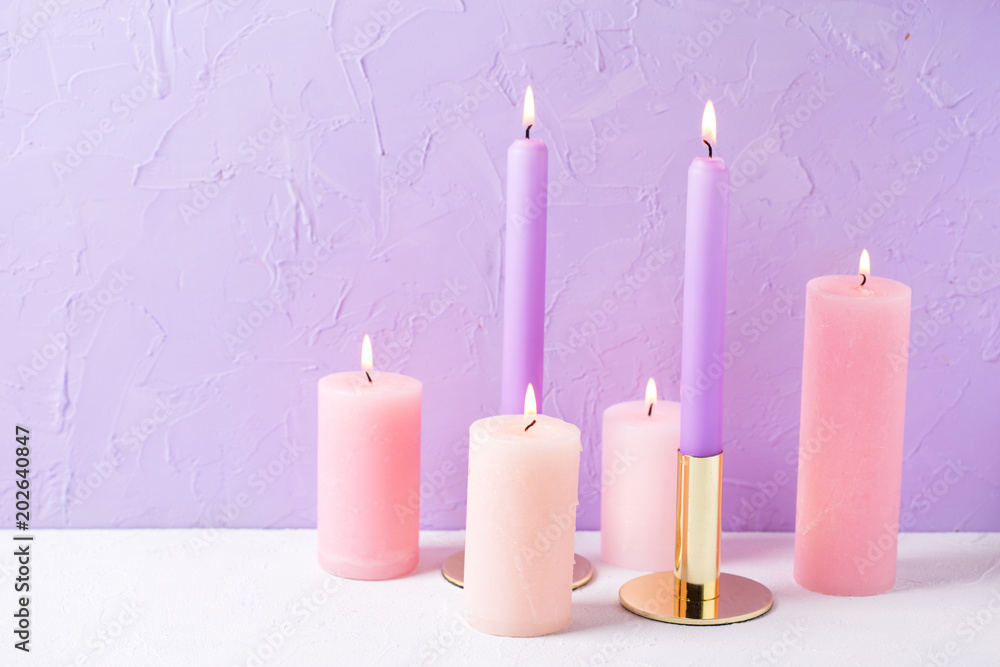 Pink color burning candles near by violet textured background. Pink color burning candles near by violet textured background.
