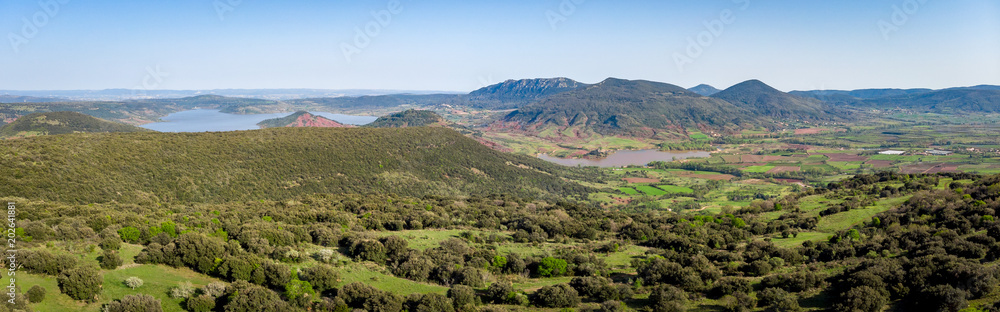 panorama aérienne sur des collines verdoyante du Languedoc avec un lac et des montagnes en fond
