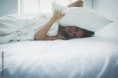 фотографія Young caucasian woman covering her head and ears with pillows