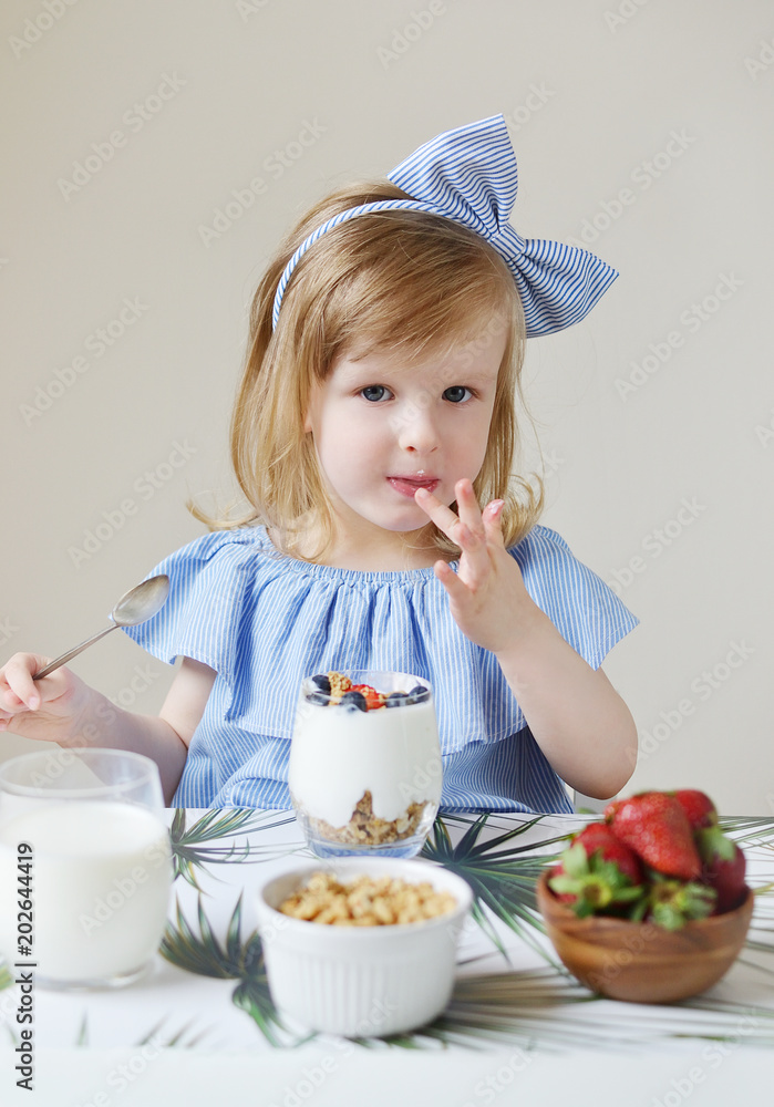 Little Caucasian Blond Girl Eating Healthy Breakfast at Home Milk Berries Strawberry Blueberry Greek Yogurt with Muesli Diet Vitamins Summer Food Concept Little Caucasian Blond Girl Eating Healthy Breakfast at Home Milk Berries Strawberry Blueberry Greek Yogurt with Muesli Diet Vitamins Summer Food Concept