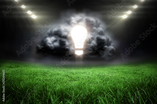 Light bulb in grey cloud against football pitch with bright lights