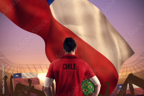 Chile football player holding ball against large football stadium under purple sky