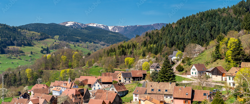 French landscape - Vosges. Panoramic view of a small village in the Vosges with snow covered mountains in the background.