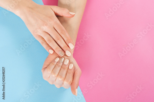 Beauty girl hand with nails manicure on blue and pink background. Manicure and Hands beauty concept. Close up  top view