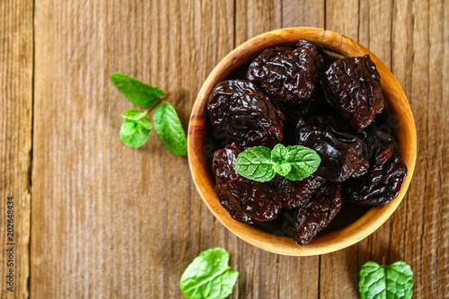 Fototapeta Naklejka Na Ścianę i Meble -  Prunes with mint leaves in a bowl on an old wooden table.