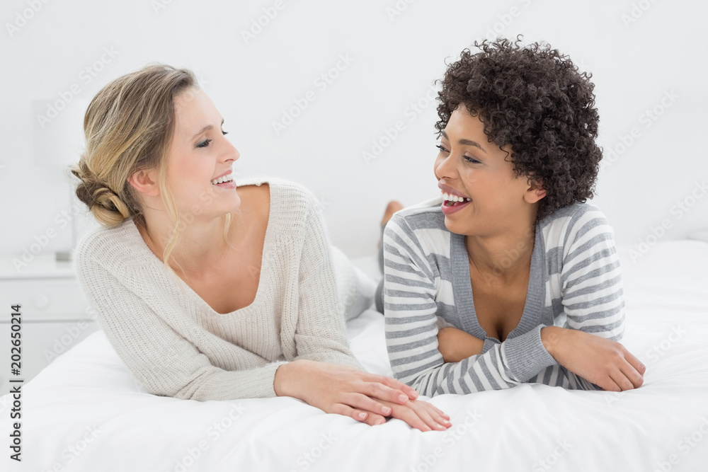 Two relaxed smiling female friends lying in bed Two relaxed smiling female friends lying in bed