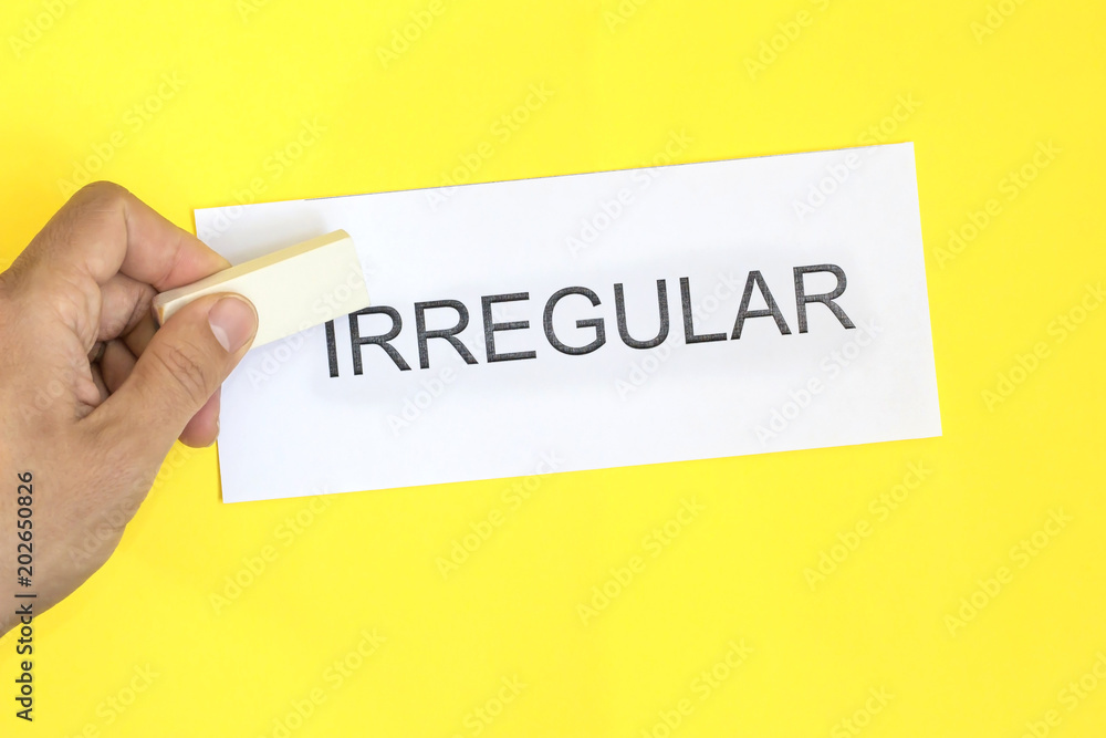 irregular is regular concept. Hand with eraser and card with word irregular irregular is regular concept. Hand with eraser and card with word irregular