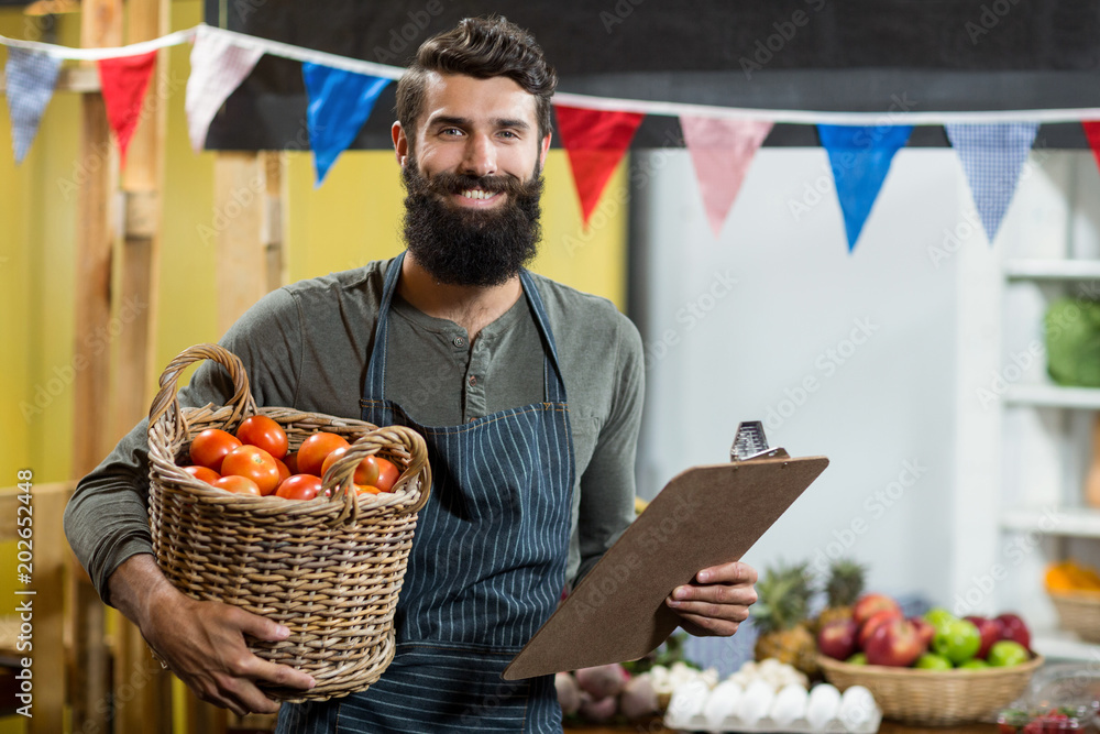 Vendor holding a clipboard and a basket of tomatoes at the grocery store Vendor holding a clipboard and a basket of tomatoes at the grocery store