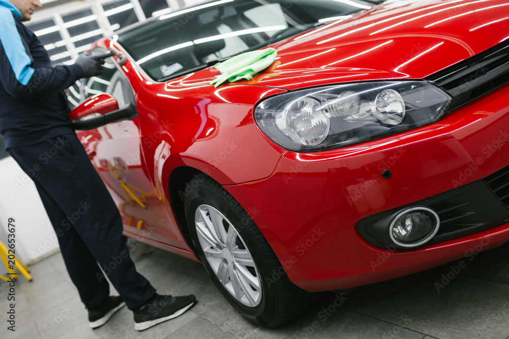 Car detailing - Man with orbital polisher in repair shop polishing car. Selective focus. 