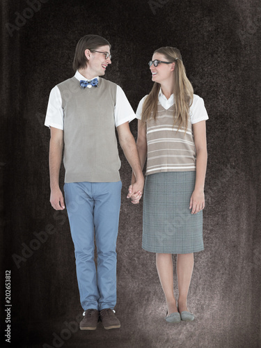 Geeky hipster couple holding hands and looking at each other against black background