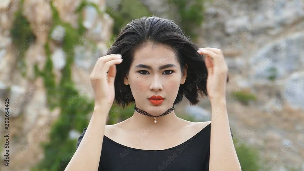 Young Asian woman looking to camera, hair blowing in wind. slow motion. Young Asian woman looking to camera, hair blowing in wind. slow motion.