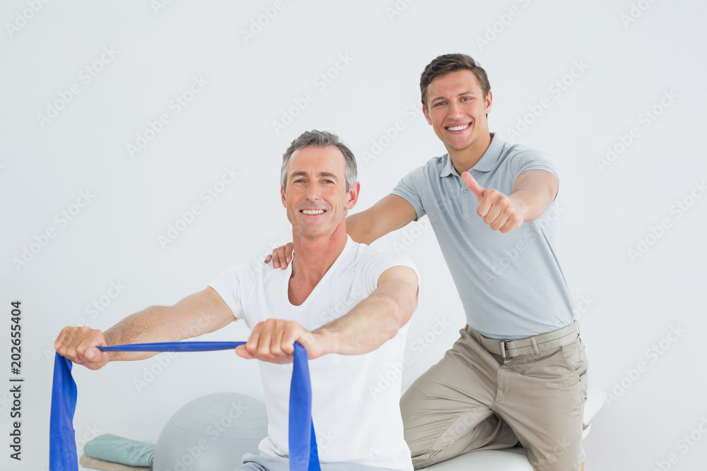 Therapist massaging a mans shoulder while gesturing thumbs up Therapist massaging a mans shoulder while gesturing thumbs up