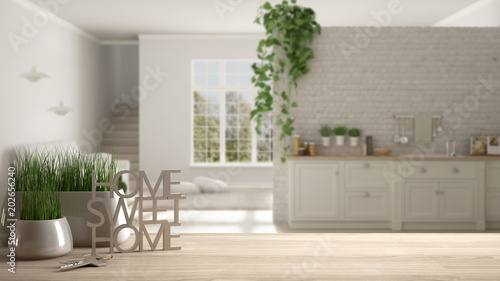 Wooden table  desk or shelf with potted grass plant  house keys and 3D letters making the words home sweet home  over kitchen with living room  architecture interior design  copy space background
