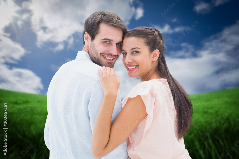 Attractive young couple smiling at camera against green field under blue sky Attractive young couple smiling at camera against green field under blue sky