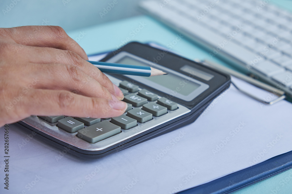Close up Business man using calculator and laptop computer for calculating with finance paper, tax, accounting, Accountant concept. Close up Business man using calculator and laptop computer for calculating with finance paper, tax, accounting, Accountant concept.