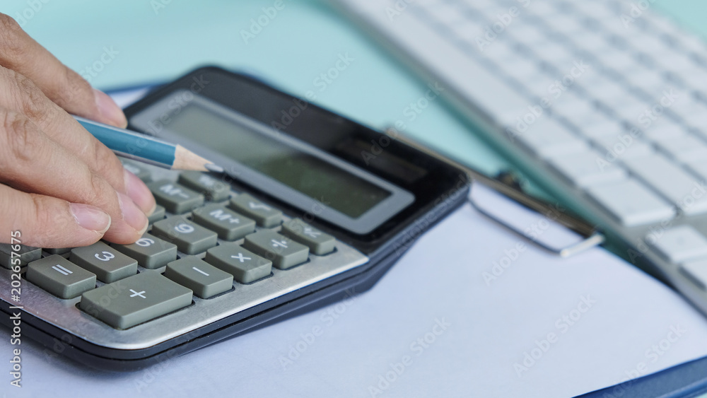 Close up Business man using calculator and laptop computer for calculating with finance paper, tax, accounting, Accountant concept. Close up Business man using calculator and laptop computer for calculating with finance paper, tax, accounting, Accountant concept.