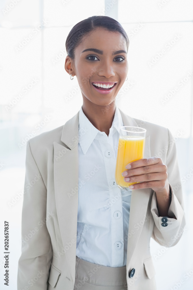 Smiling elegant businesswoman holding glass of orange juice Smiling elegant businesswoman holding glass of orange juice